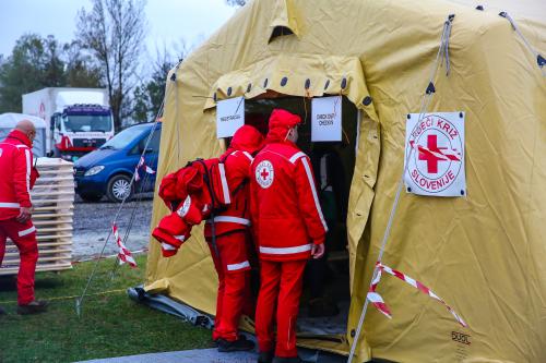 V šotor rumene barve kjer je napis Rdeči križ Slovenije vstopata dve osebi v uniformi Rdečega križa.