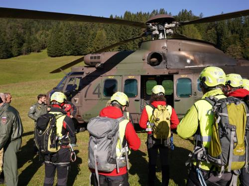Šest gorskih reševalcev vstopa v vojški helikopter na levi strani trije letalski piloti.